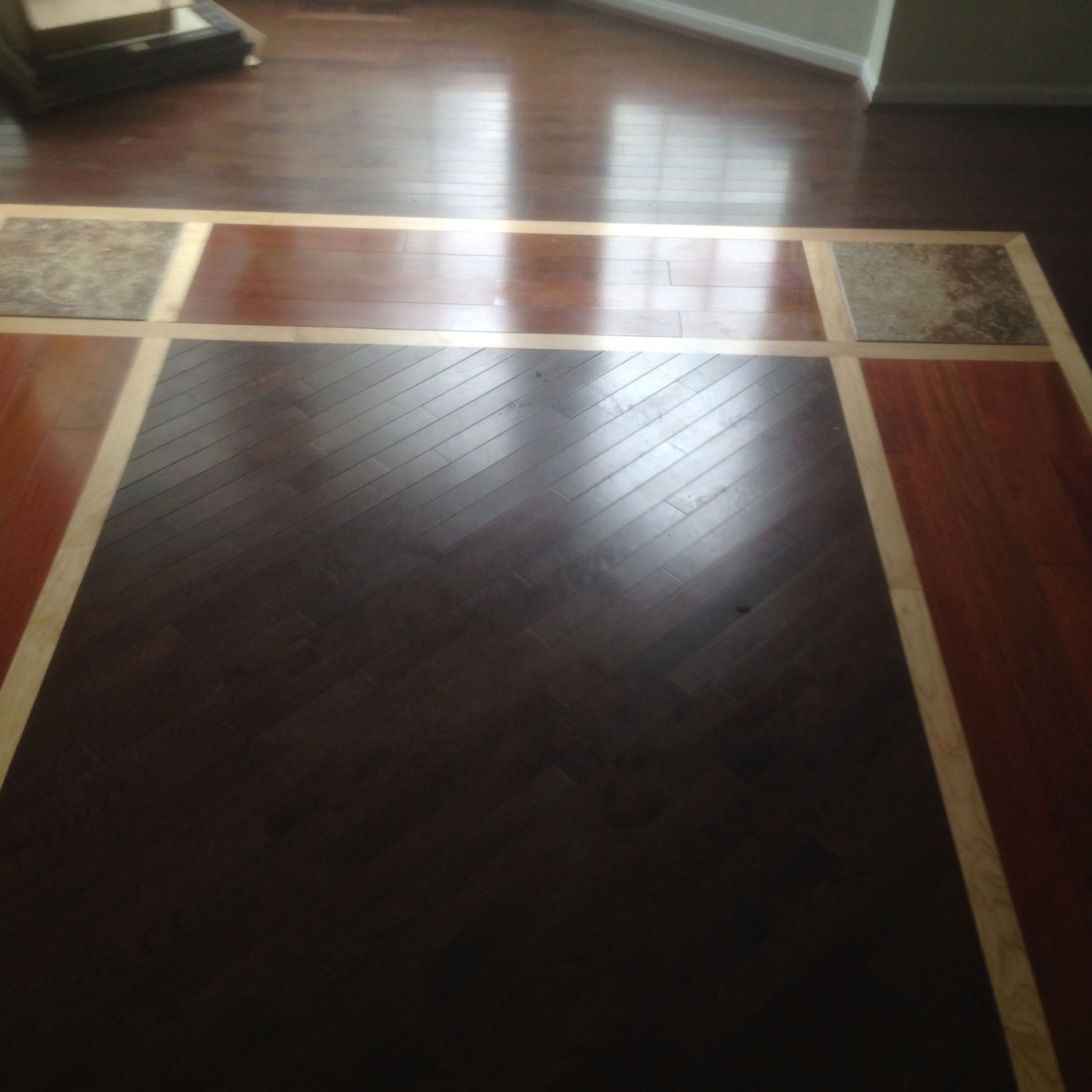 Dark hardwood floor with inlaid lighter wood and stone accents.