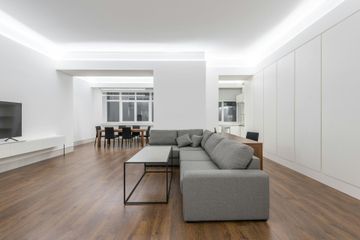 Modern, minimalist living room with gray sectional sofa, wood floors, white walls, and built-in storage.