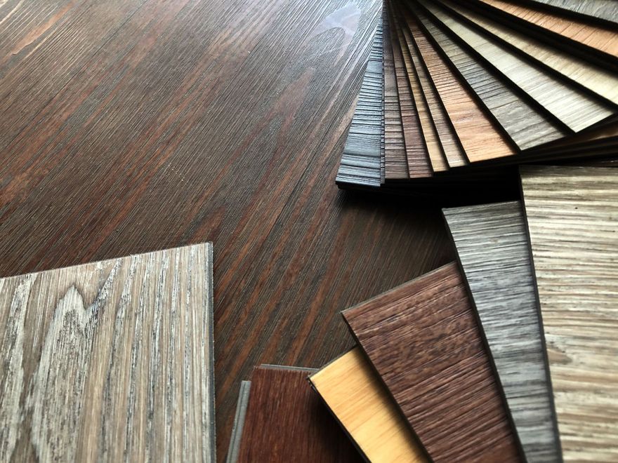 Various wood-look flooring samples on a dark wood surface.