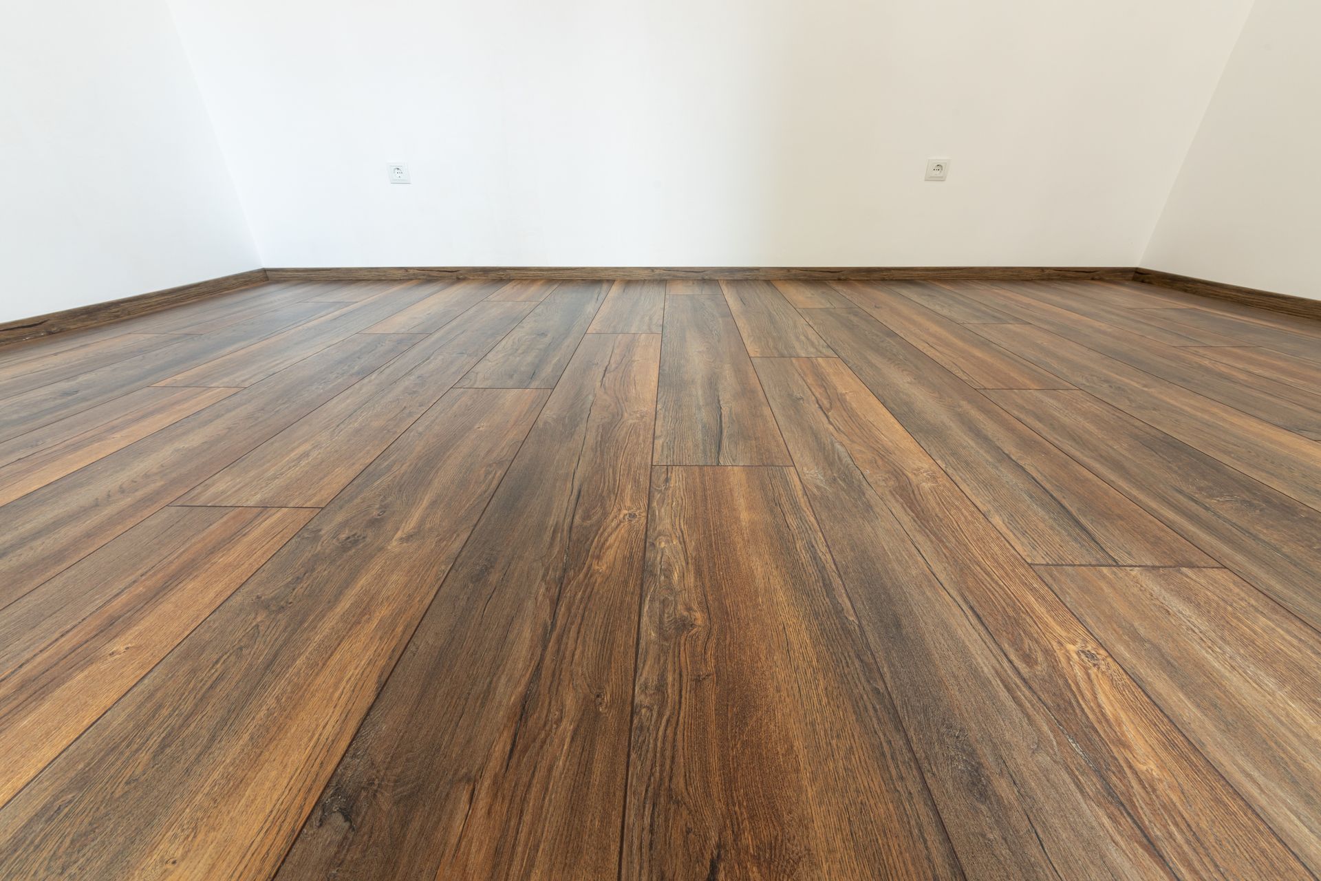 Empty room with white walls and wood-look flooring, viewed from floor level