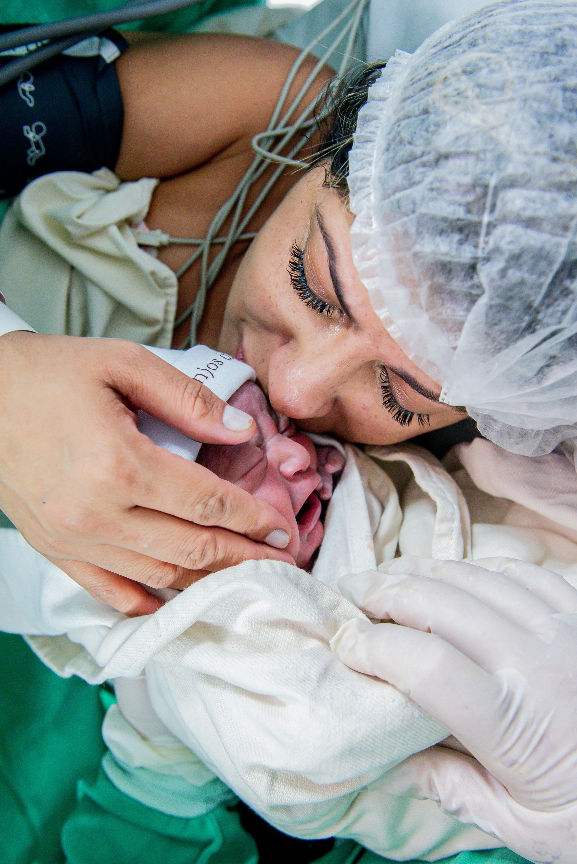 Mother kisses newborn baby after birth in a hospital.