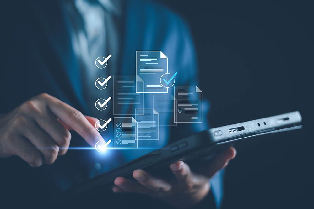 Person in a suit using a tablet with digital documents and checkmarks, signifying approval.