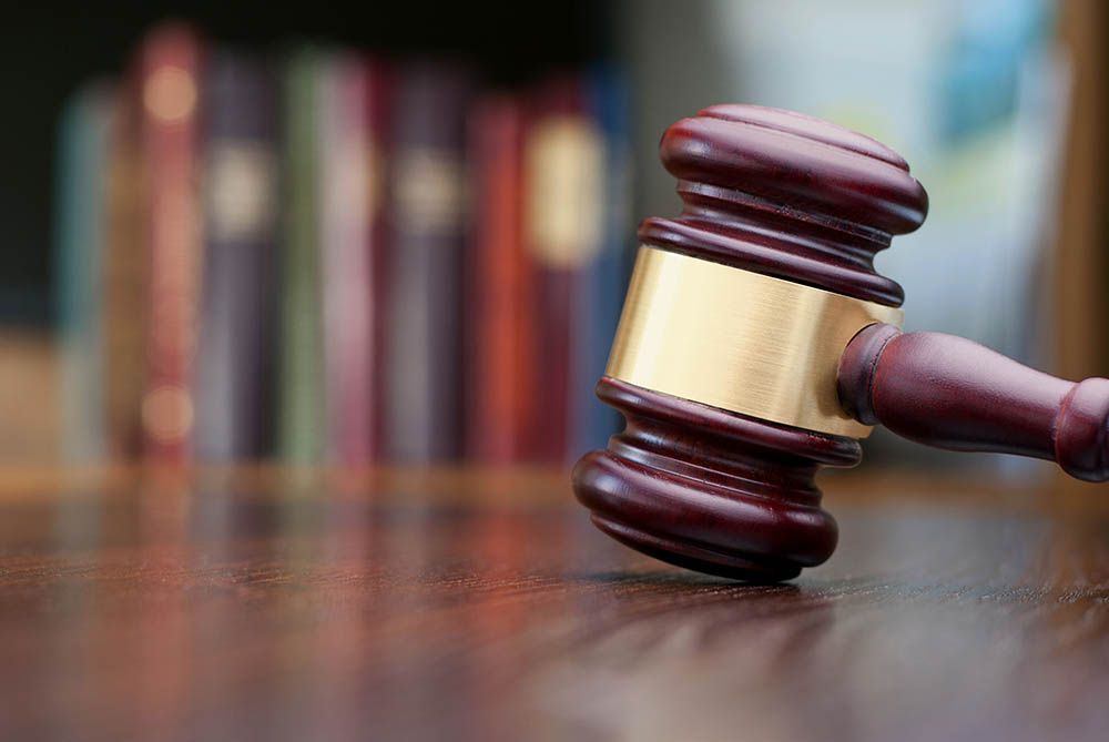 Wooden gavel on a desk in front of a blurred bookshelf.