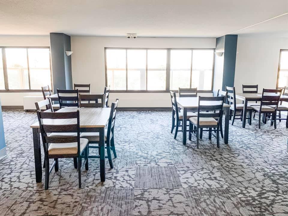 Apartment complex community center with three tables with two chair each.