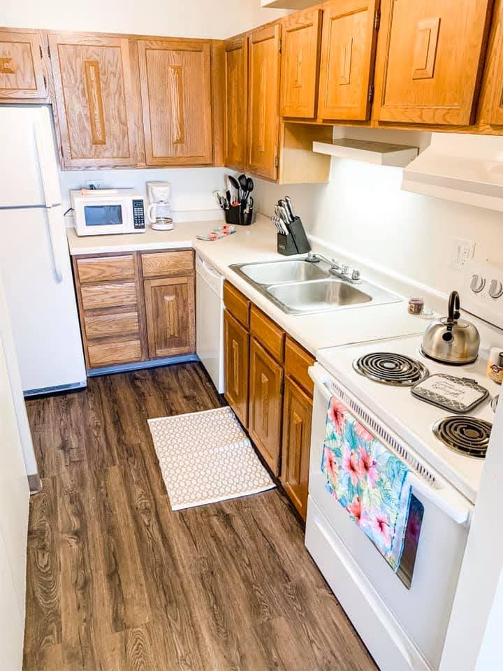 Kitchen with light wood cabinets and white stove and white refrigerator.