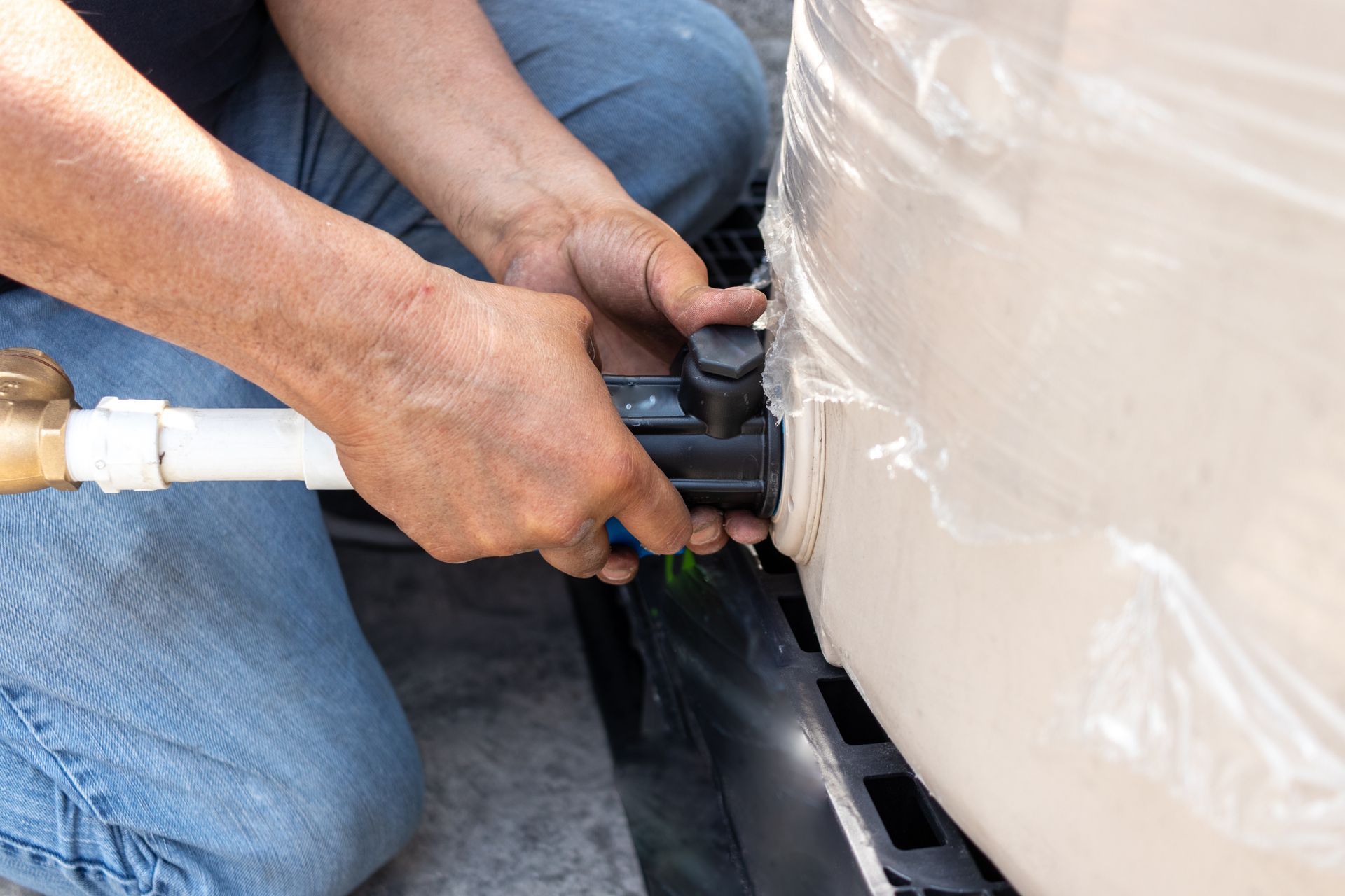 A professional holding a pipe is installing a water cistern.