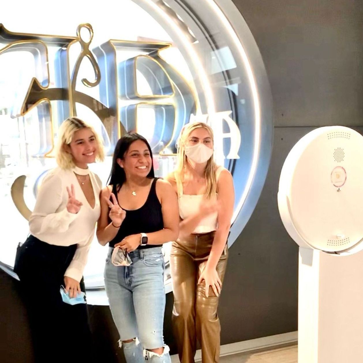 Three women taking photos in a photo booth