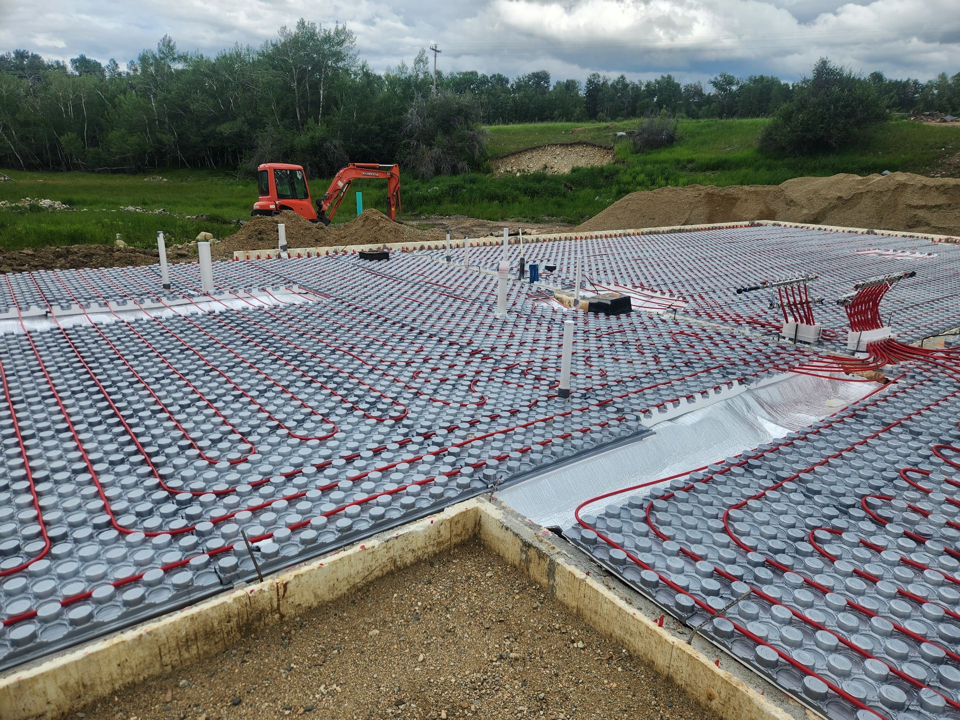 A construction site with a lot of pipes on the ground and a bulldozer in the background.