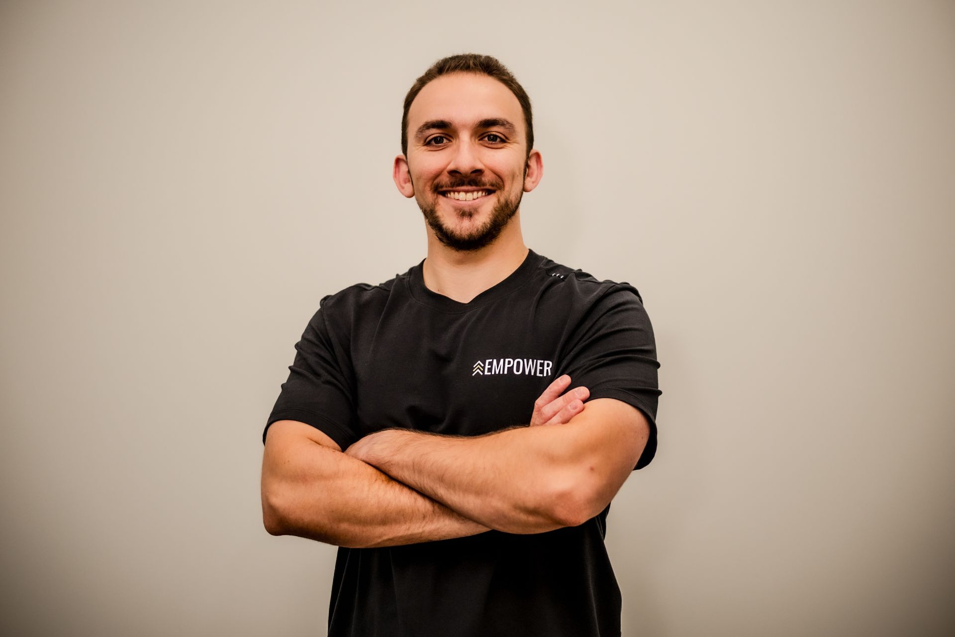 Man with crossed arms, smiling, wearing a black t-shirt.