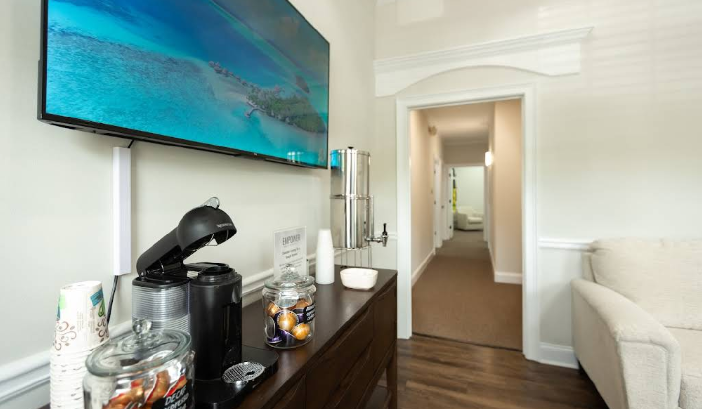 A coffee station in an office, with a hallway leading to more rooms.