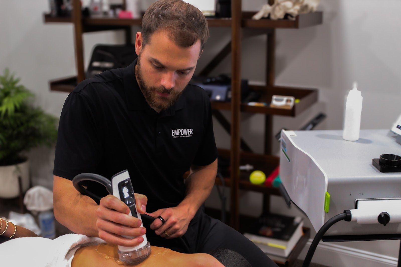 Man using an electric clipper on a client’s back during a treatment in a clinic room