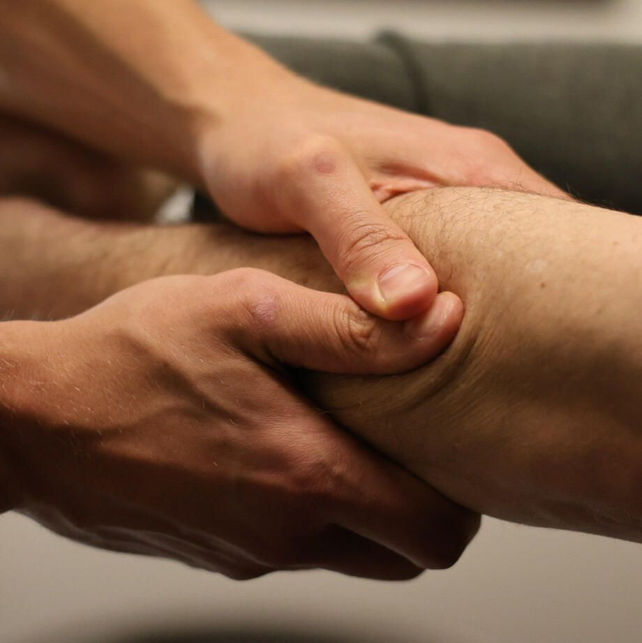 Hands examining an arm, possibly for a medical assessment. Skin is light, setting is indoors.