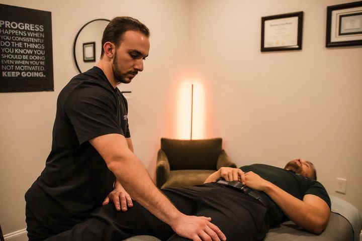 A person receiving physical therapy from a therapist in a light-filled office.