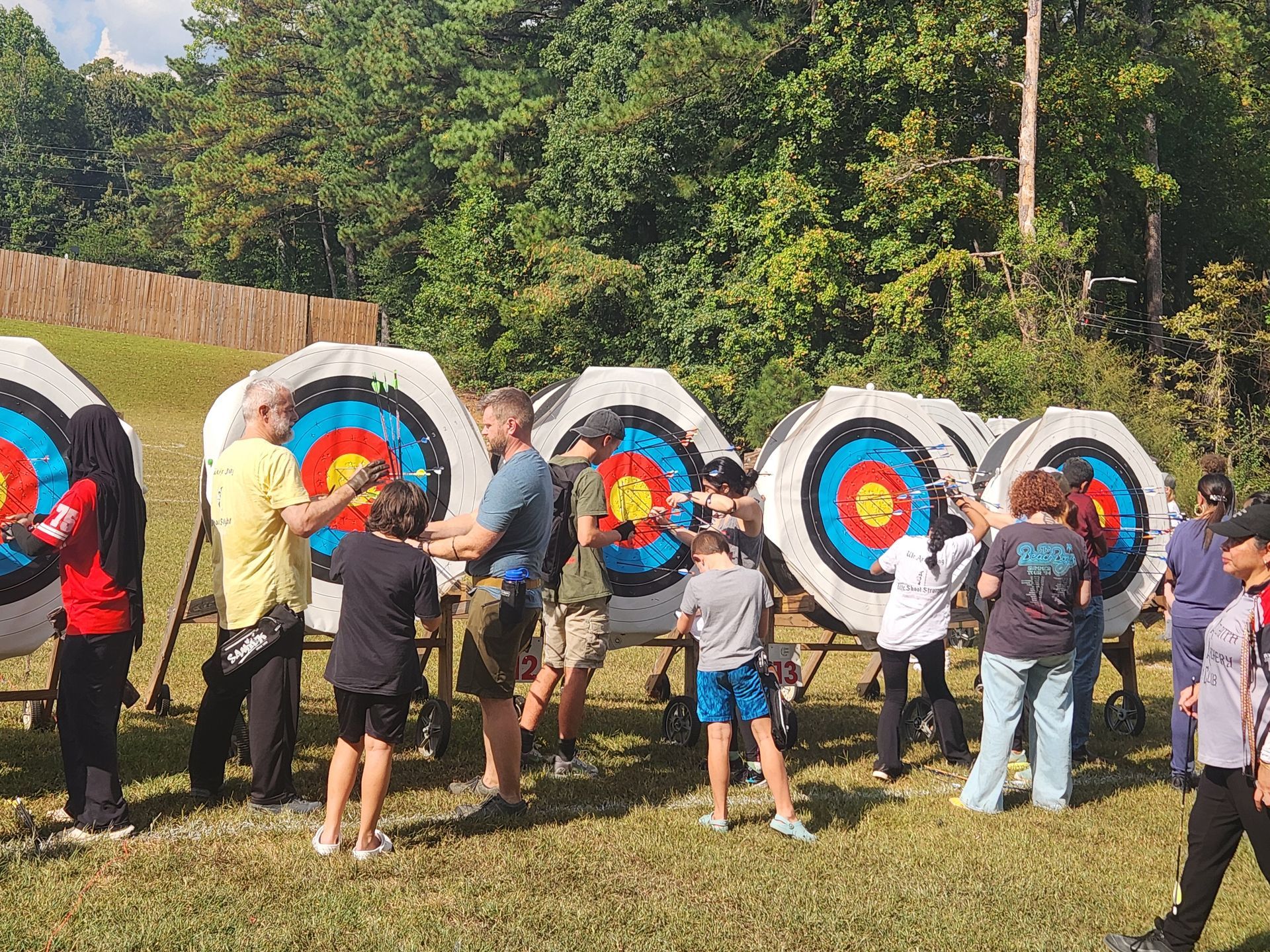 People standing at outdoor archery targets with colorful bullseyes in a grassy field