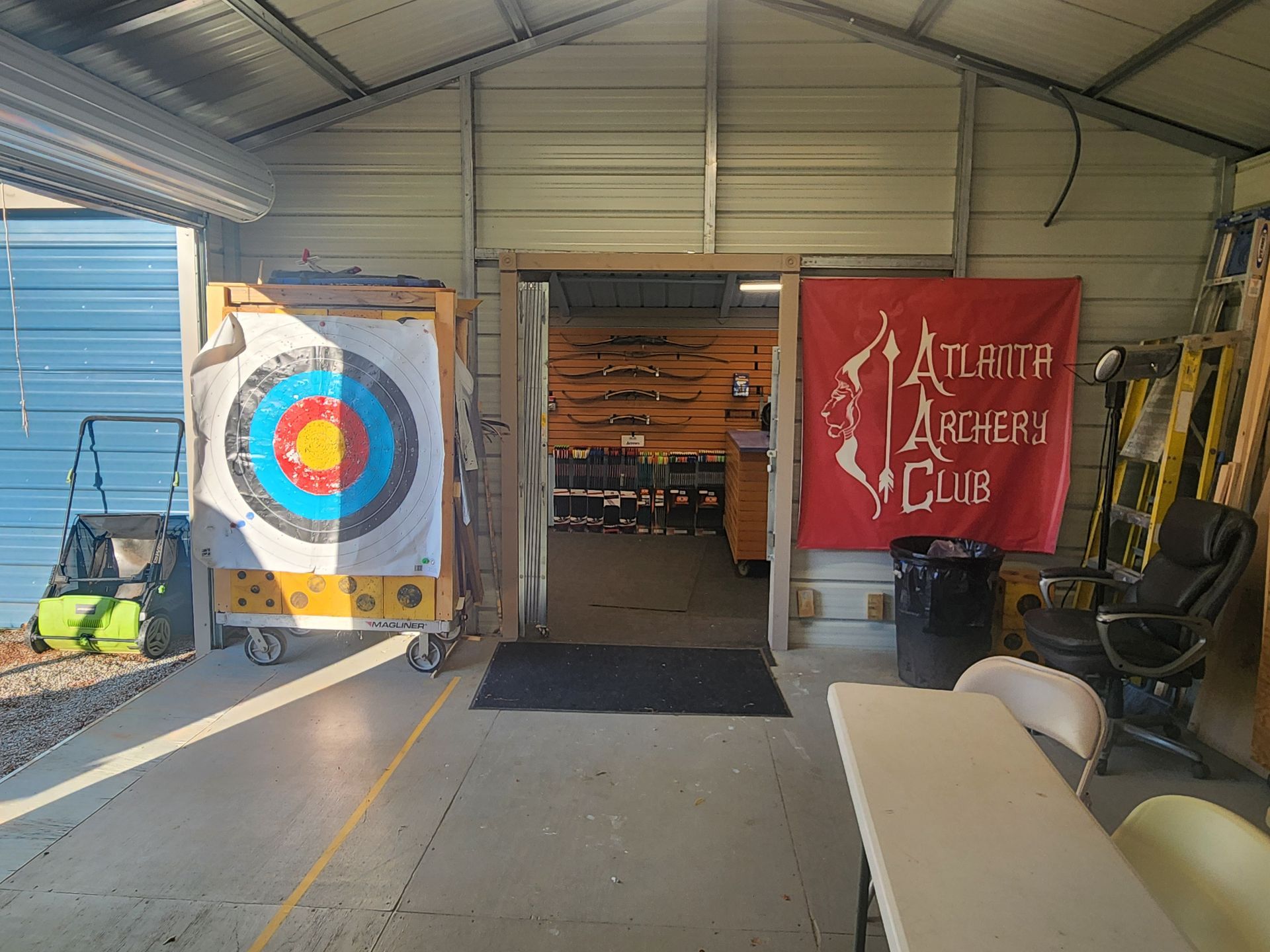 Indoor archery range with a target on the left and Atlanta Archery Club banner on the right.