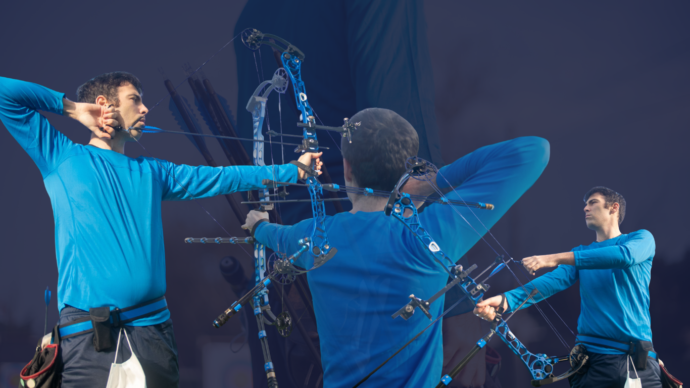 Archers in blue shirts aiming bows at targets in a dark indoor range