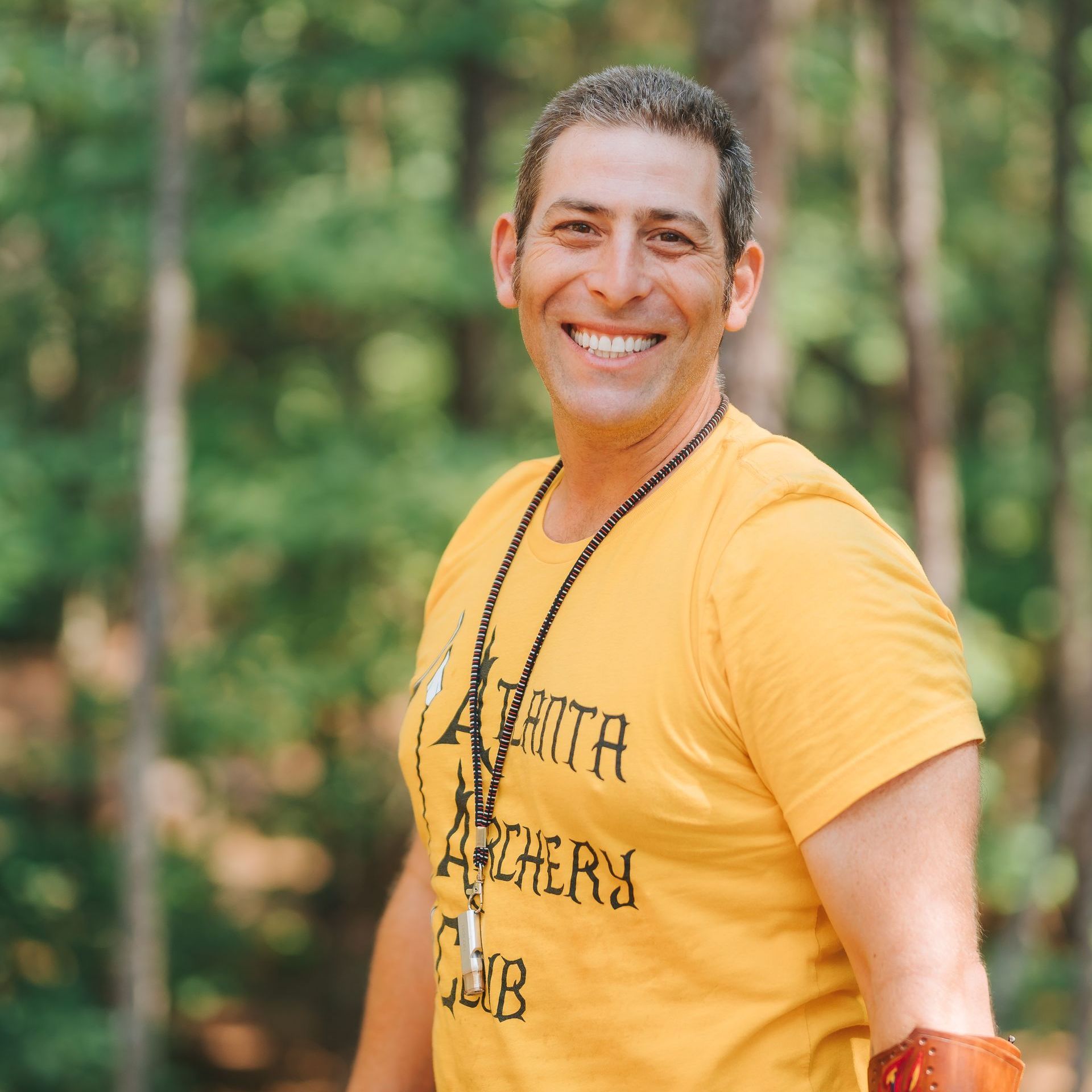 Man smiles, wearing yellow t-shirt that says 