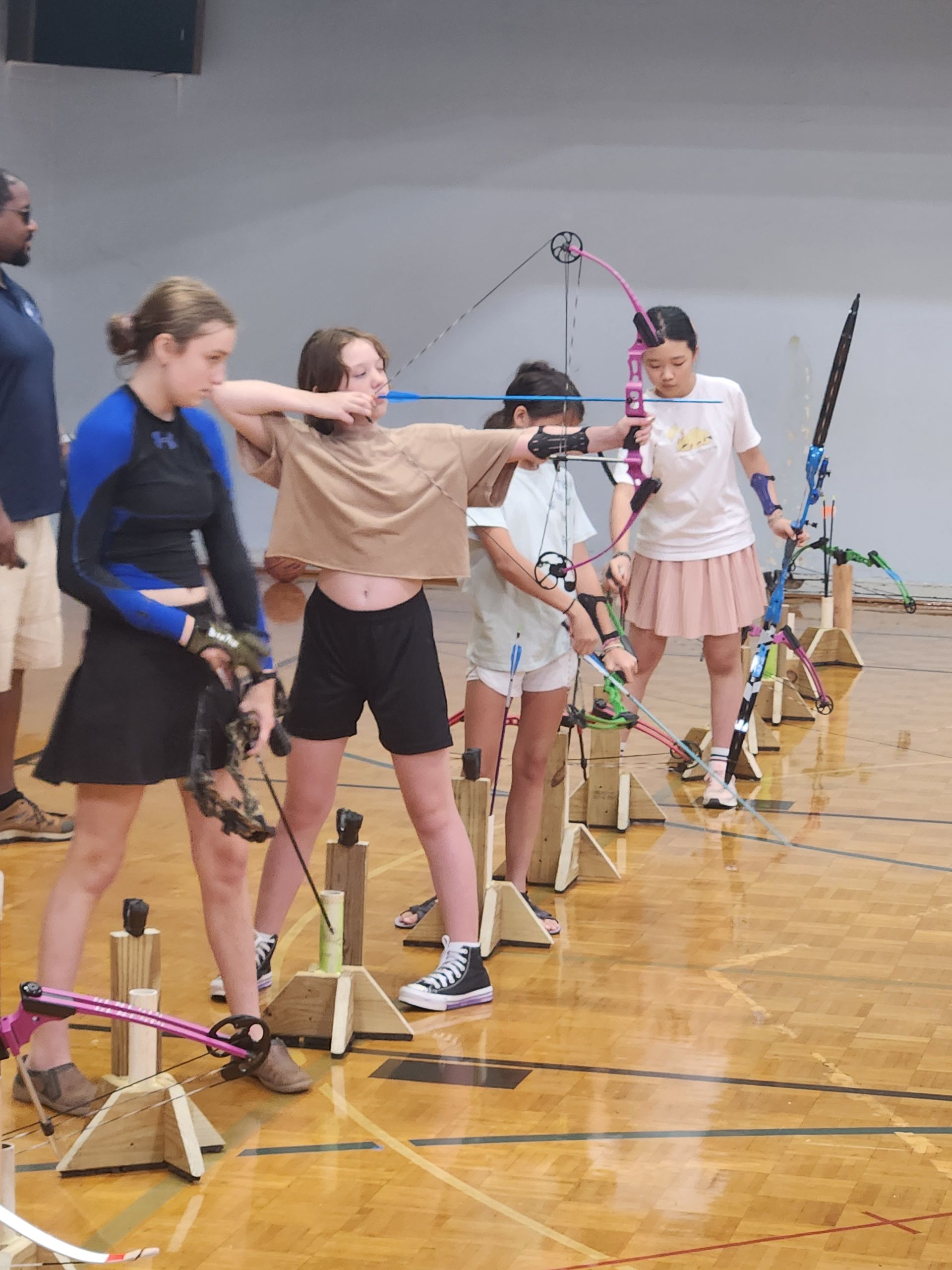 Archers aiming bows in a row during an indoor archery practice session