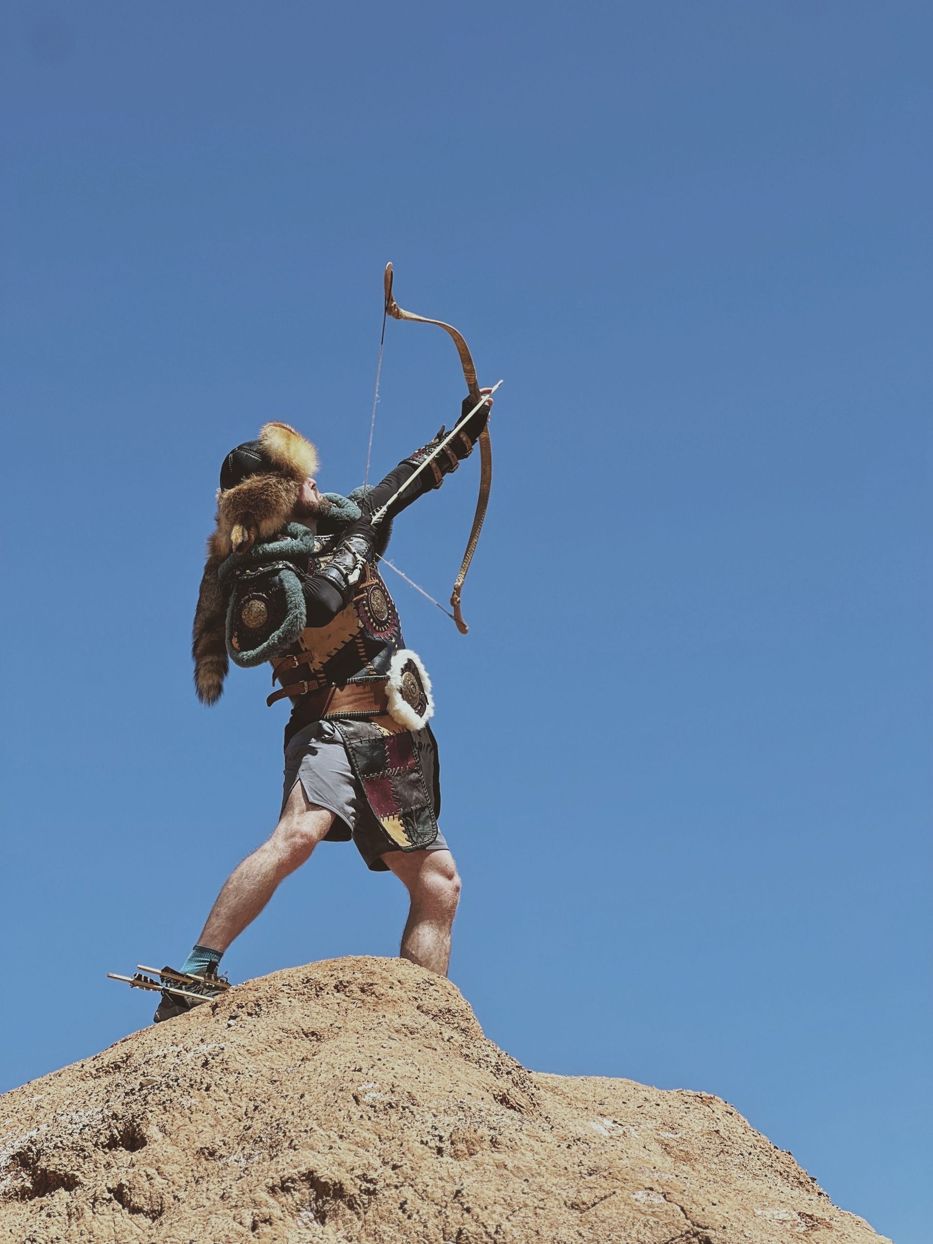 Archer in blue stands before two targets on a grassy archery range.