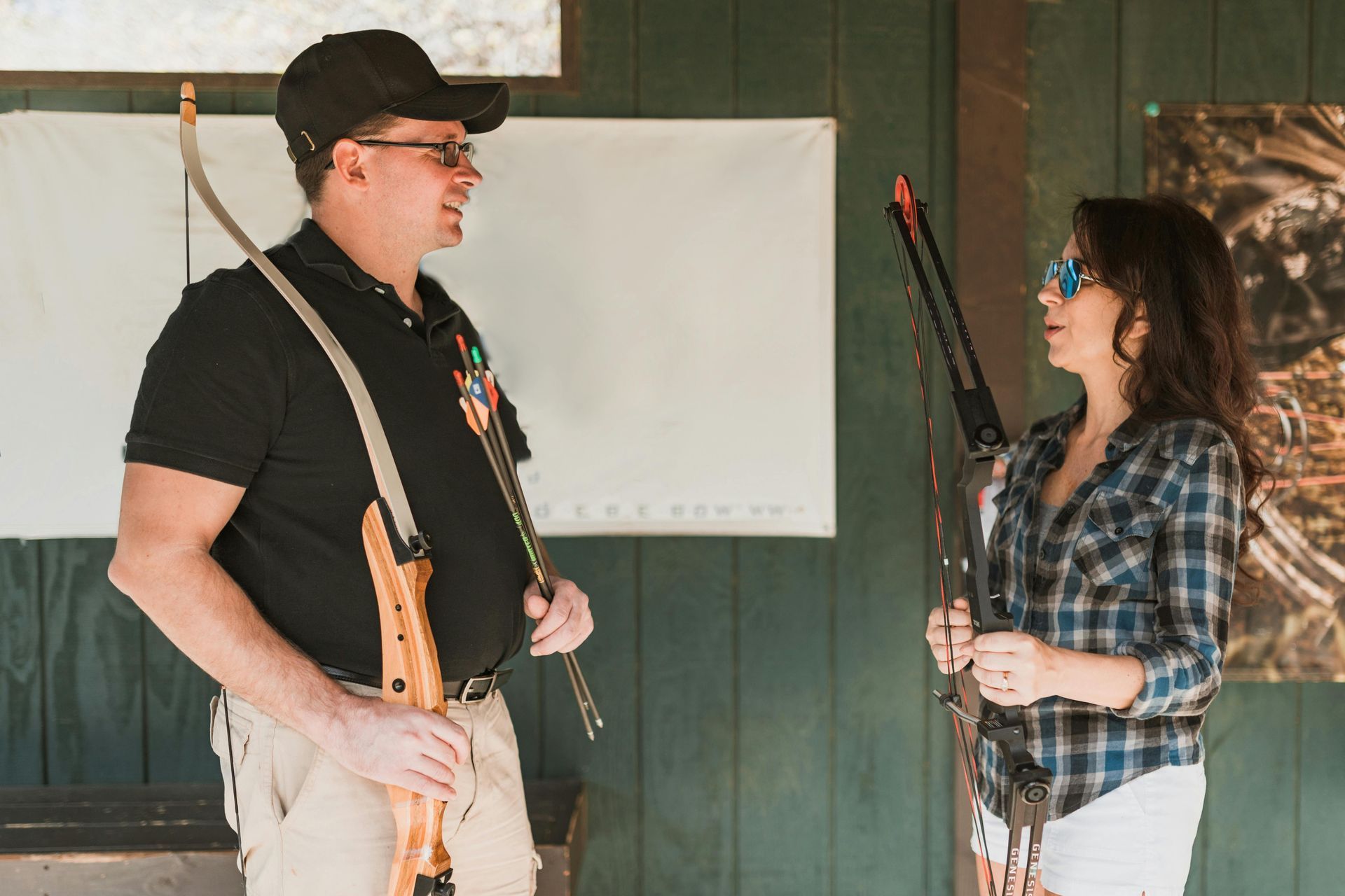 Two people holding rifles face each other in an indoor shooting range.