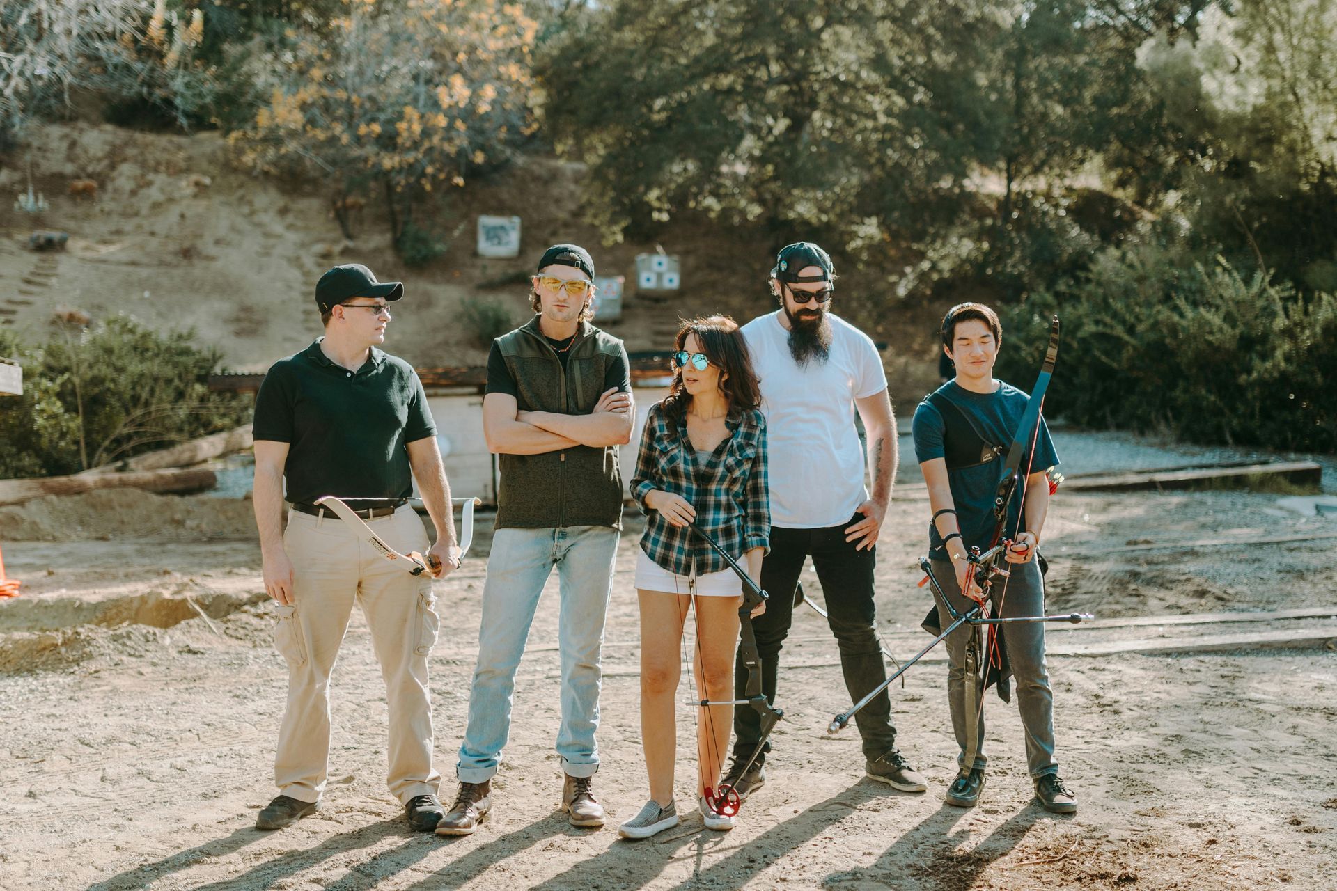 Five people standing together outdoors on a dirt path in front of rocky hills and trees