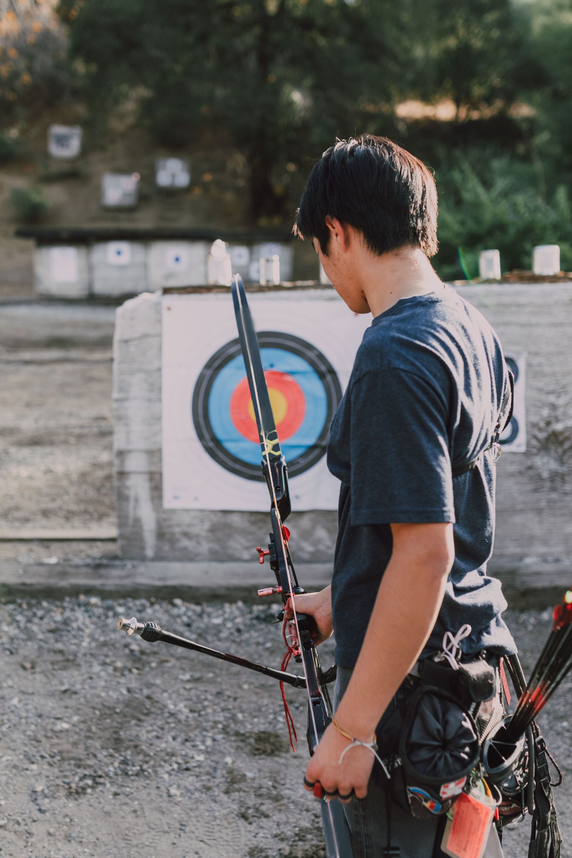 Archer in blue stands before two targets on a grassy archery range.