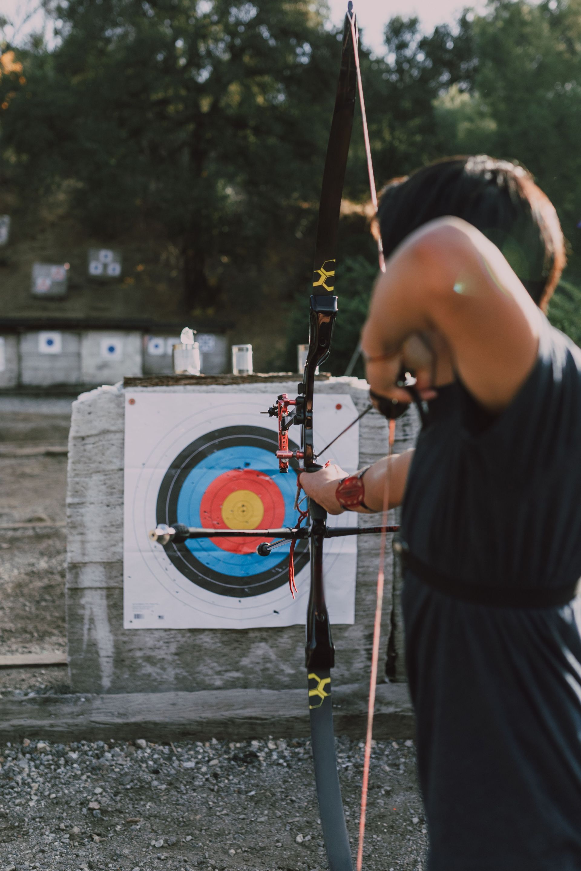 Archer in blue stands before two targets on a grassy archery range.