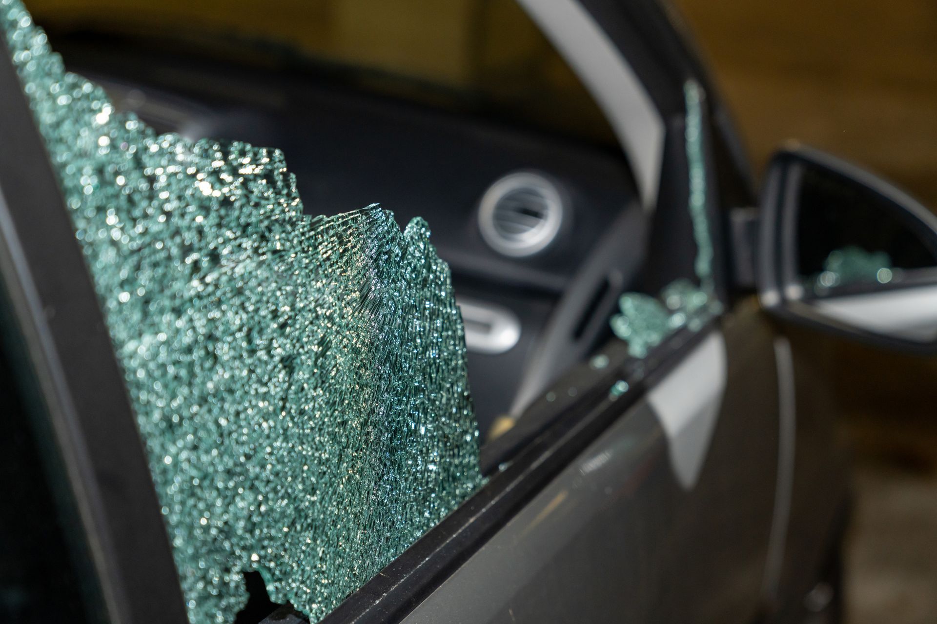 A car with a broken windshield is parked in a garage.