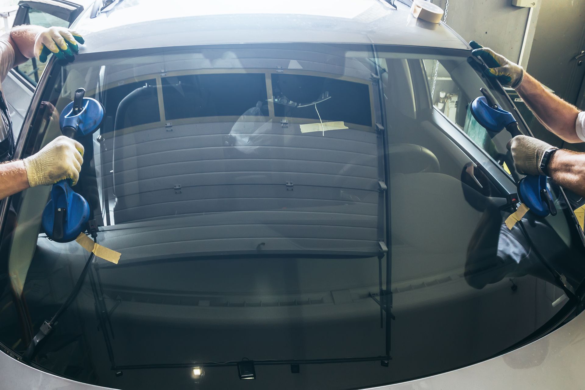 Two men are installing a windshield on a car.