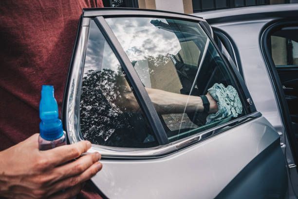 A person is cleaning a car window with a spray bottle.