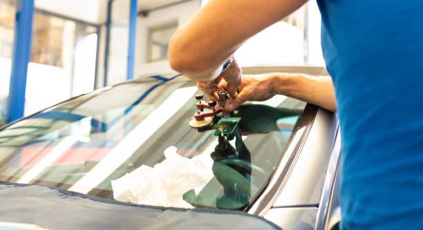 A person is fixing a windshield on a car.