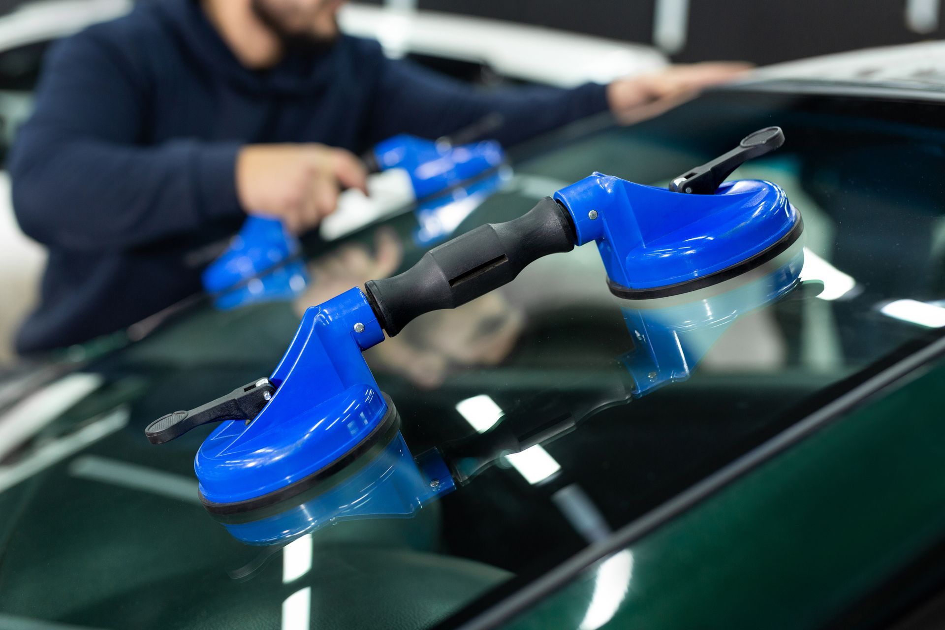 A man is installing a windshield on a car.