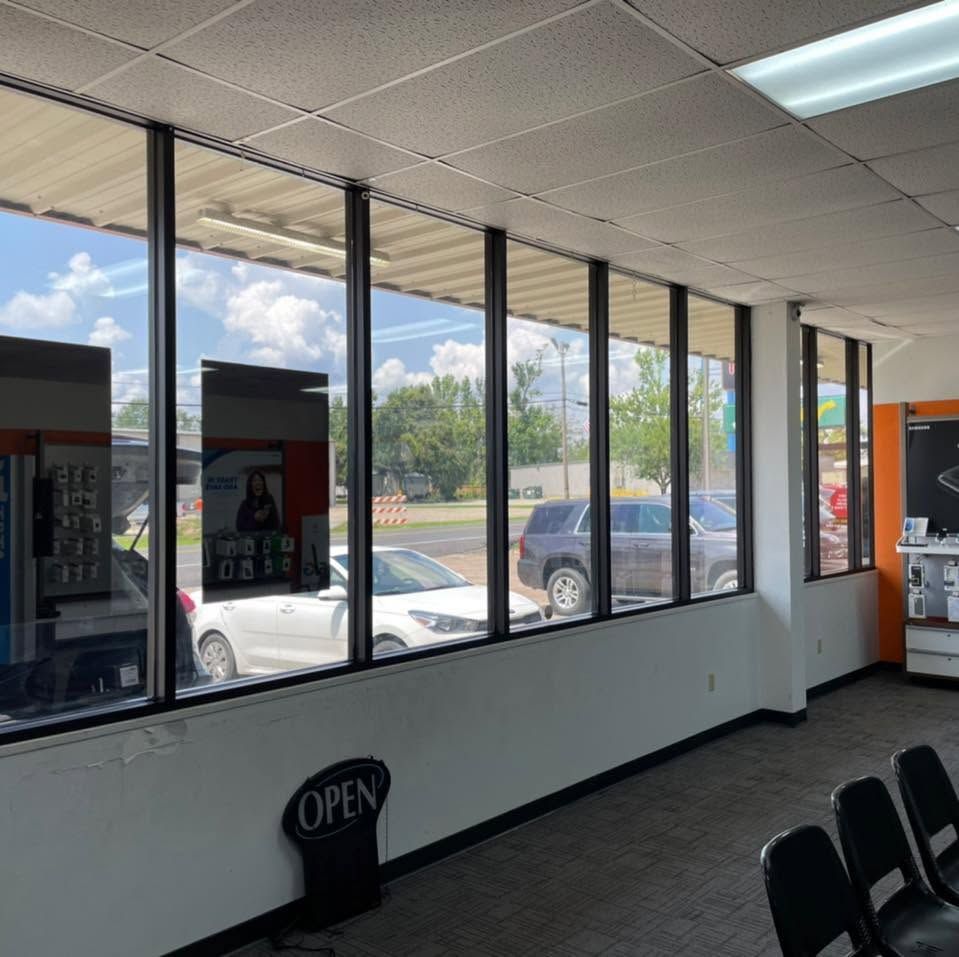 Inside a store with large windows, an OPEN sign and parked cars visible outside.