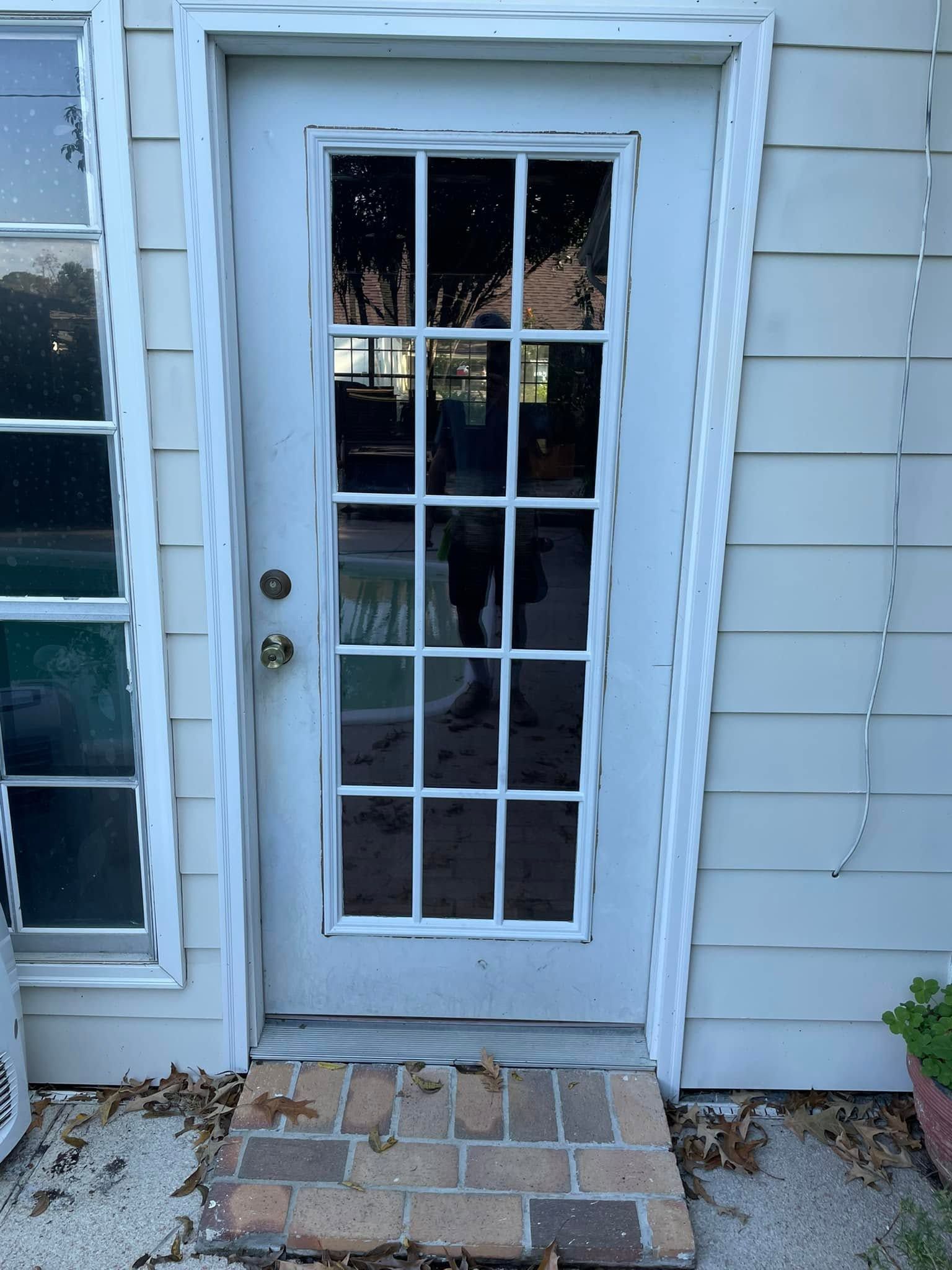 Back door with glass panes and white siding, brick step, and a small outdoor light string on the right