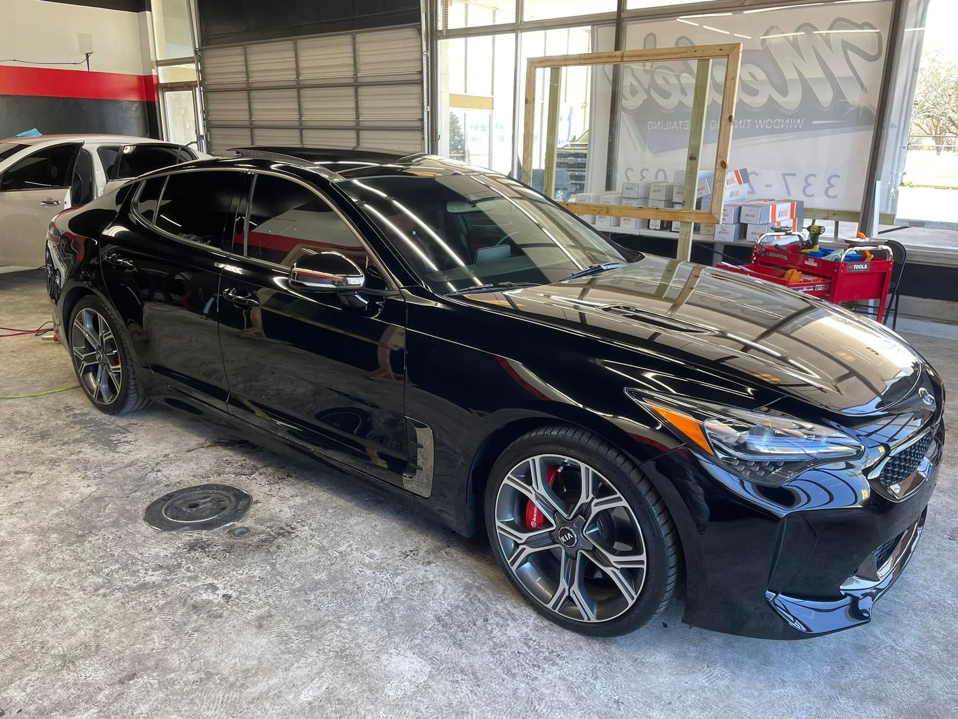 Black sports sedan parked inside a garage, viewed from the front-left side.