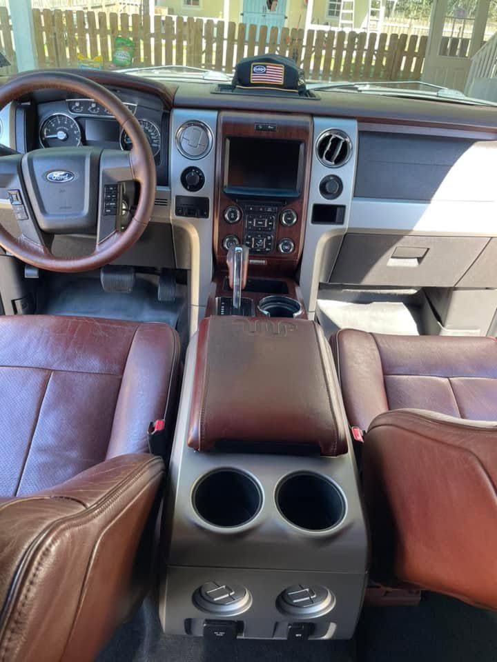 Car interior with brown leather seats, center console cup holders, and dashboard view of the front cabin