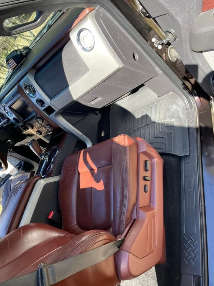 Car interior with brown leather seats, center console, and floor mat in bright sunlight