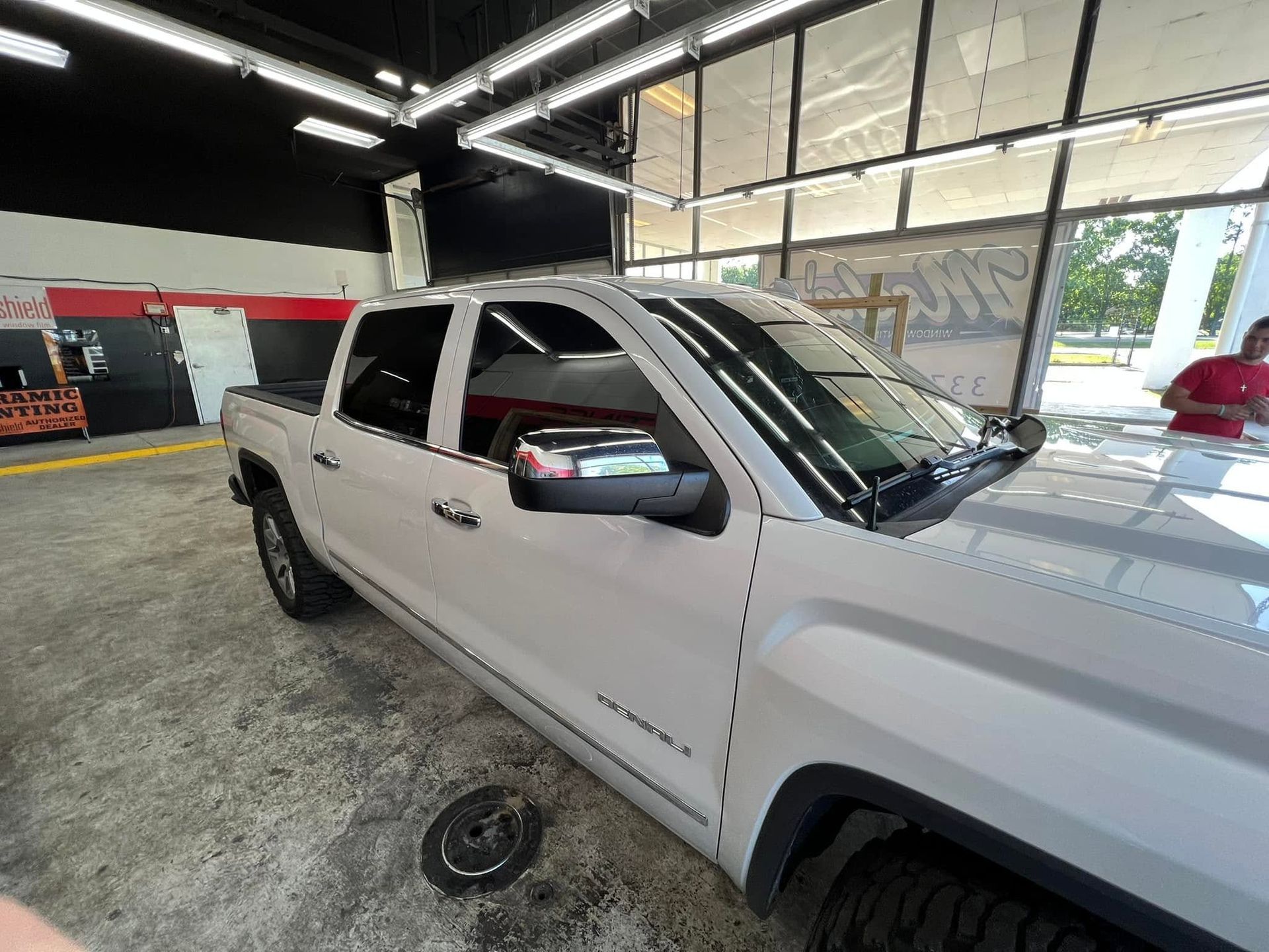 White pickup truck inside an auto shop garage, seen from the front passenger side.