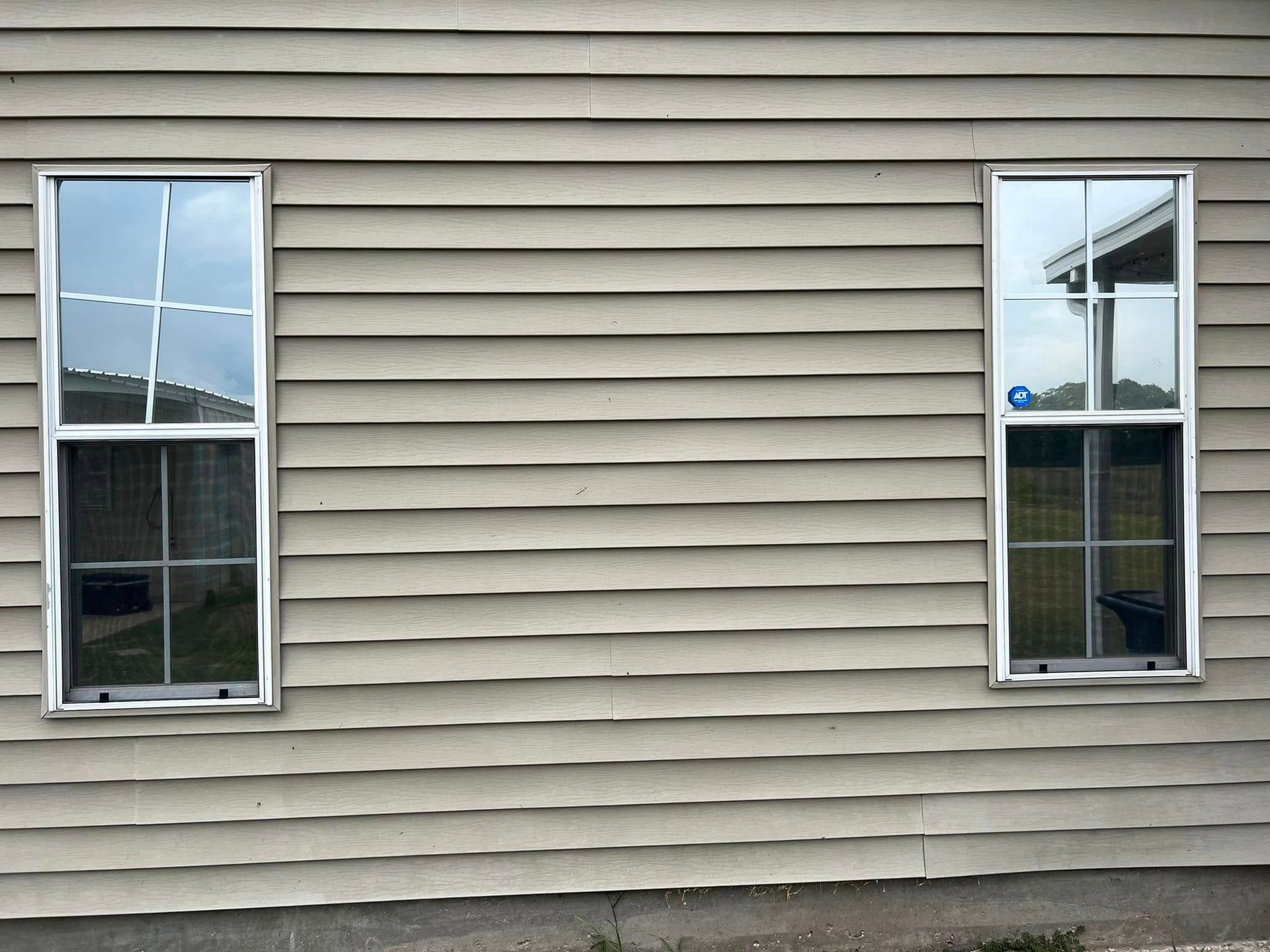 Exterior house siding with two narrow windows on a beige wall