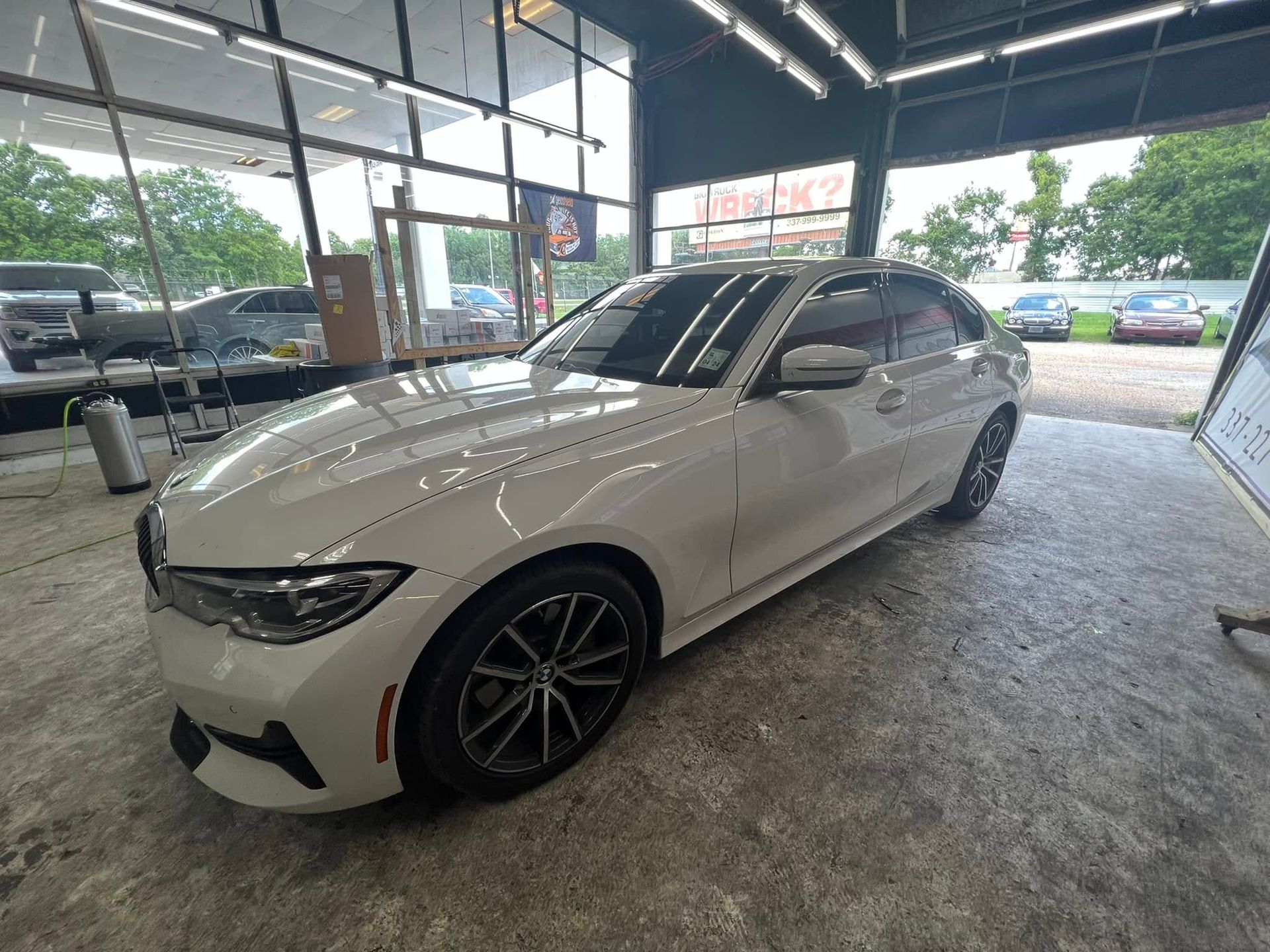 White BMW coupe parked inside a covered showroom or garage.