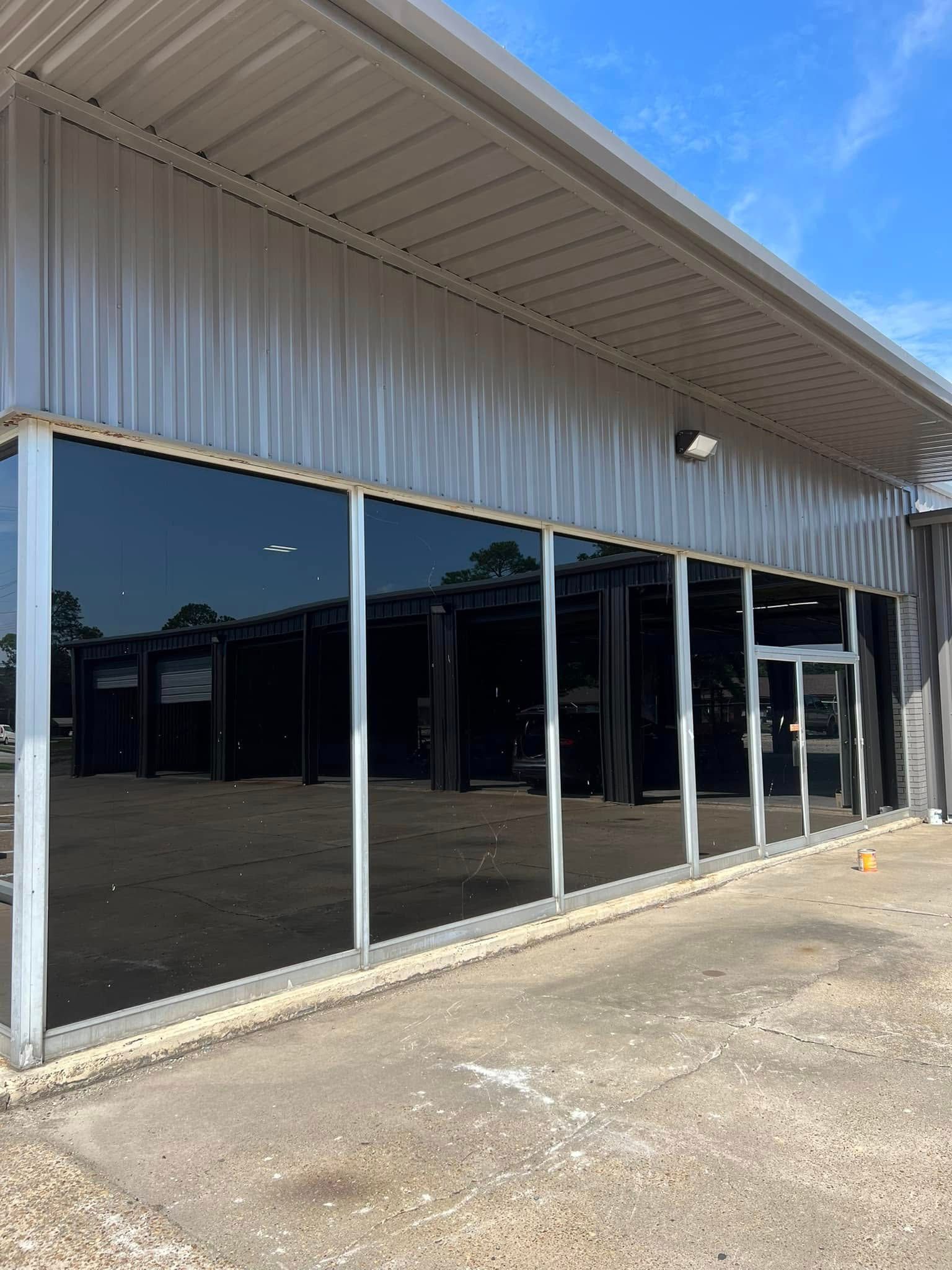 Empty storefront with dark reflective windows and a metal awning on a sunny day
