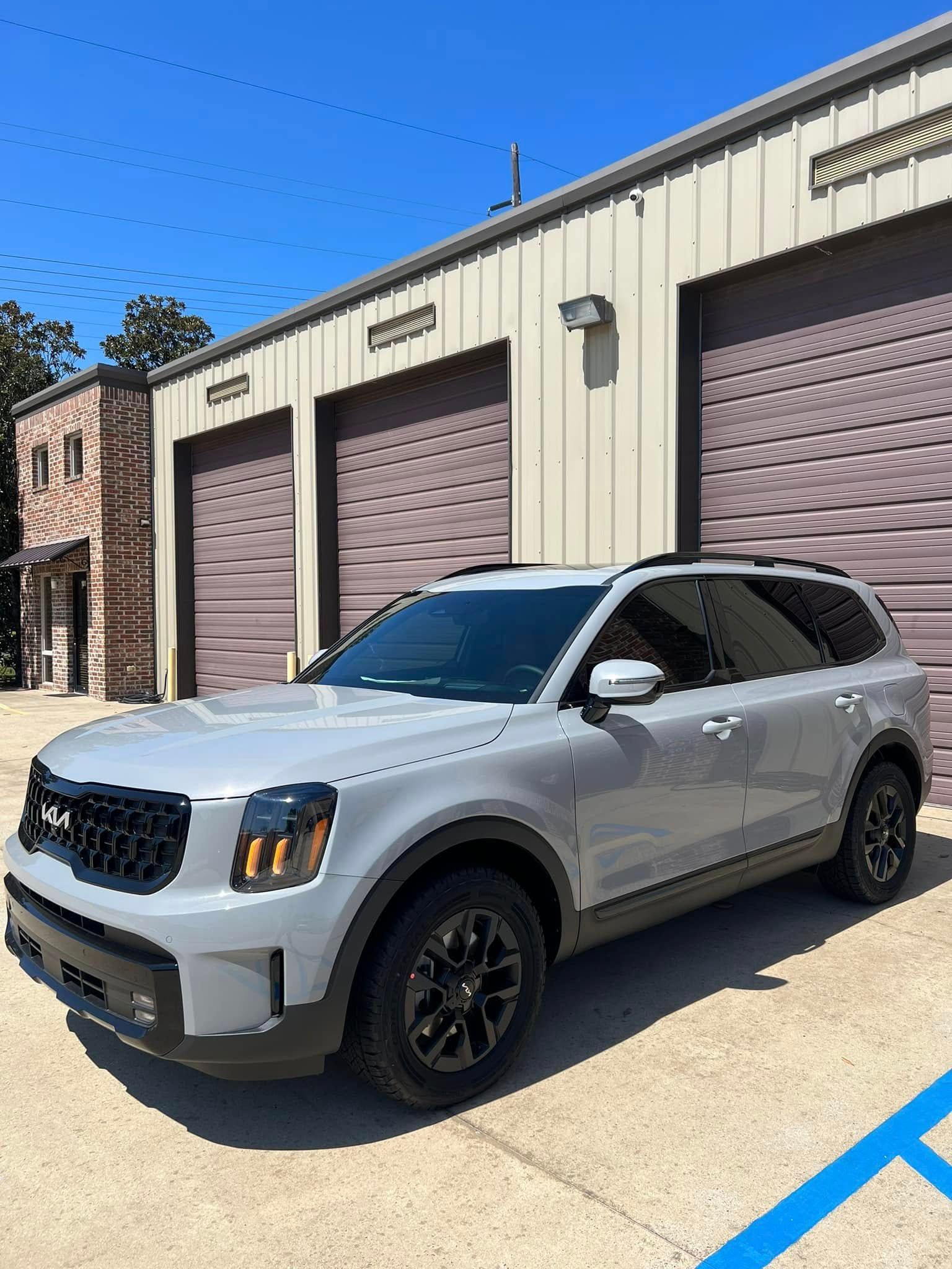 Silver SUV parked outside beige garage bays on a sunny day
