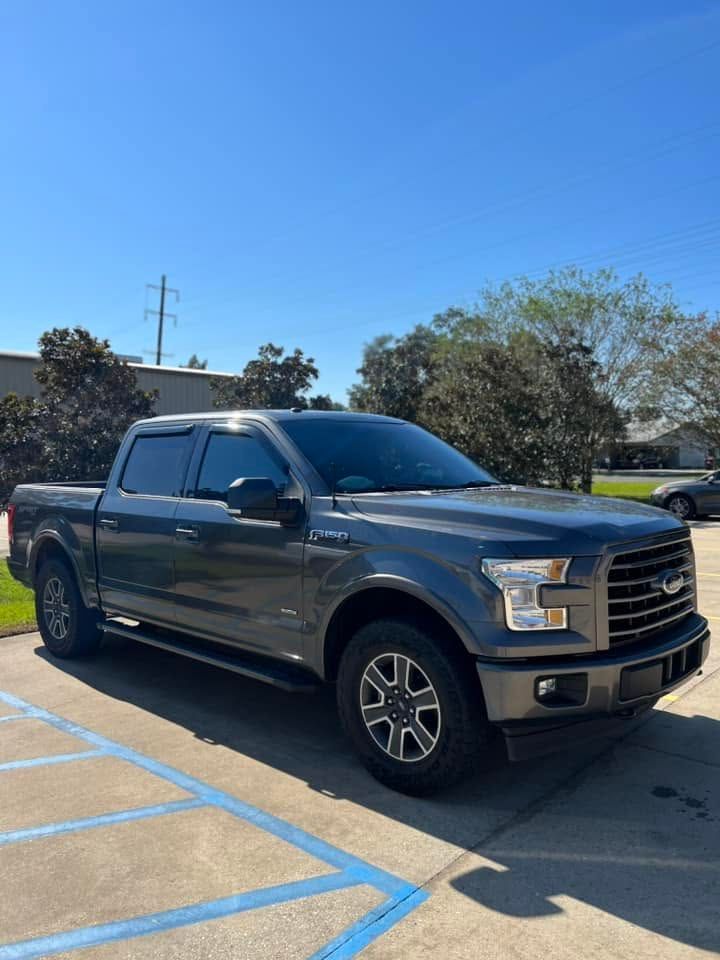 Gray pickup truck parked in a sunny lot with blue handicap lines and clear sky.