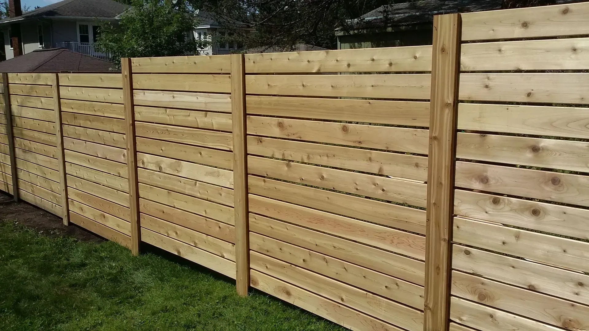 A wooden fence is sitting in the grass in front of a house.