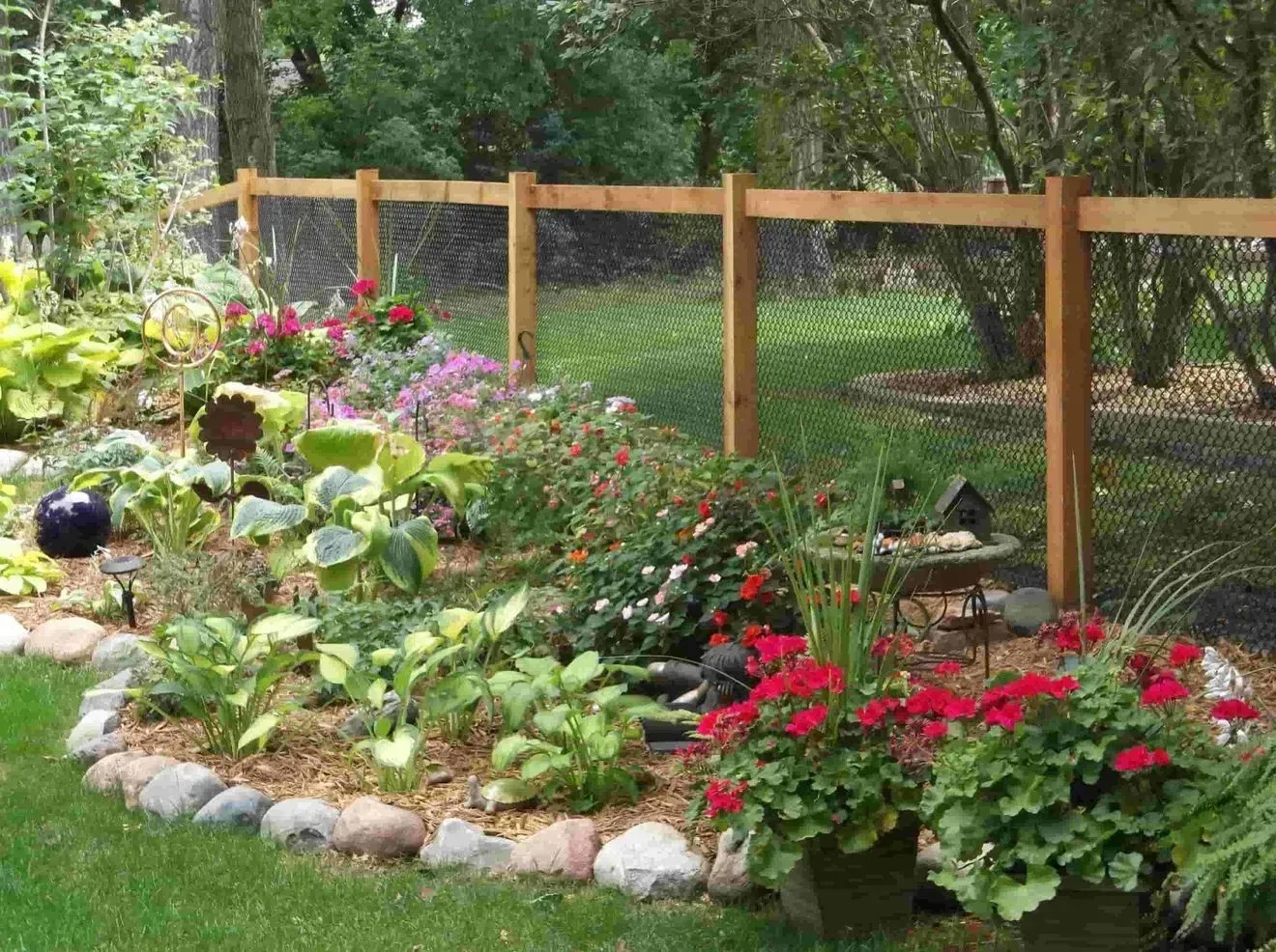 A wooden fence surrounds a garden filled with flowers and plants.
