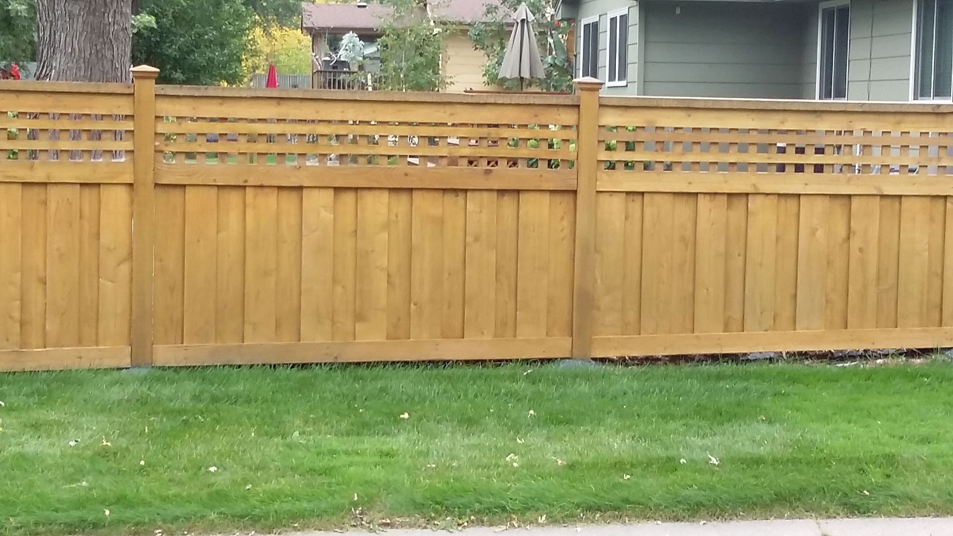 Wooden backyard fence with horizontal slats and green grass in front