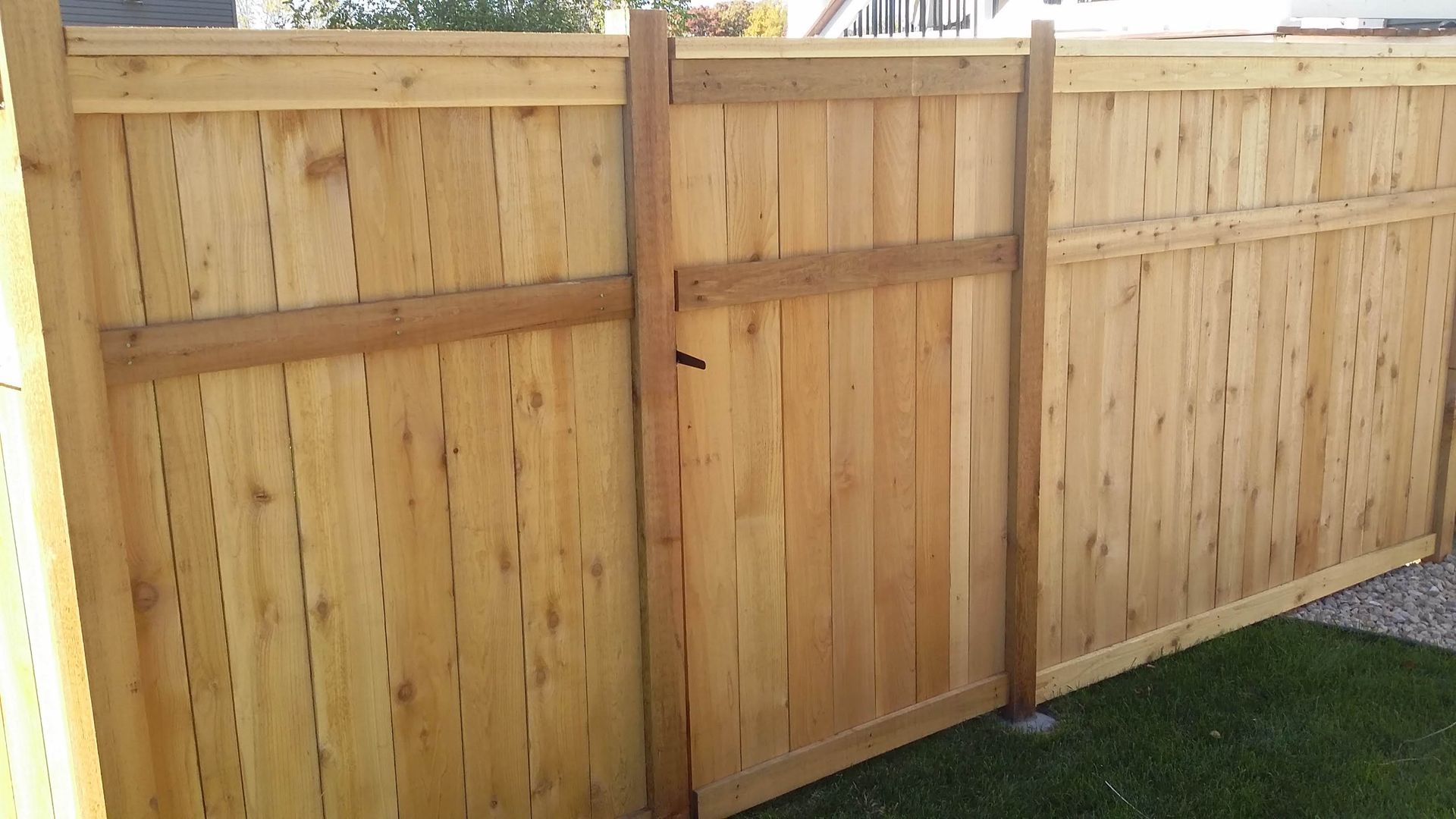 Wooden privacy fence with a gate beside a patch of grass outdoors