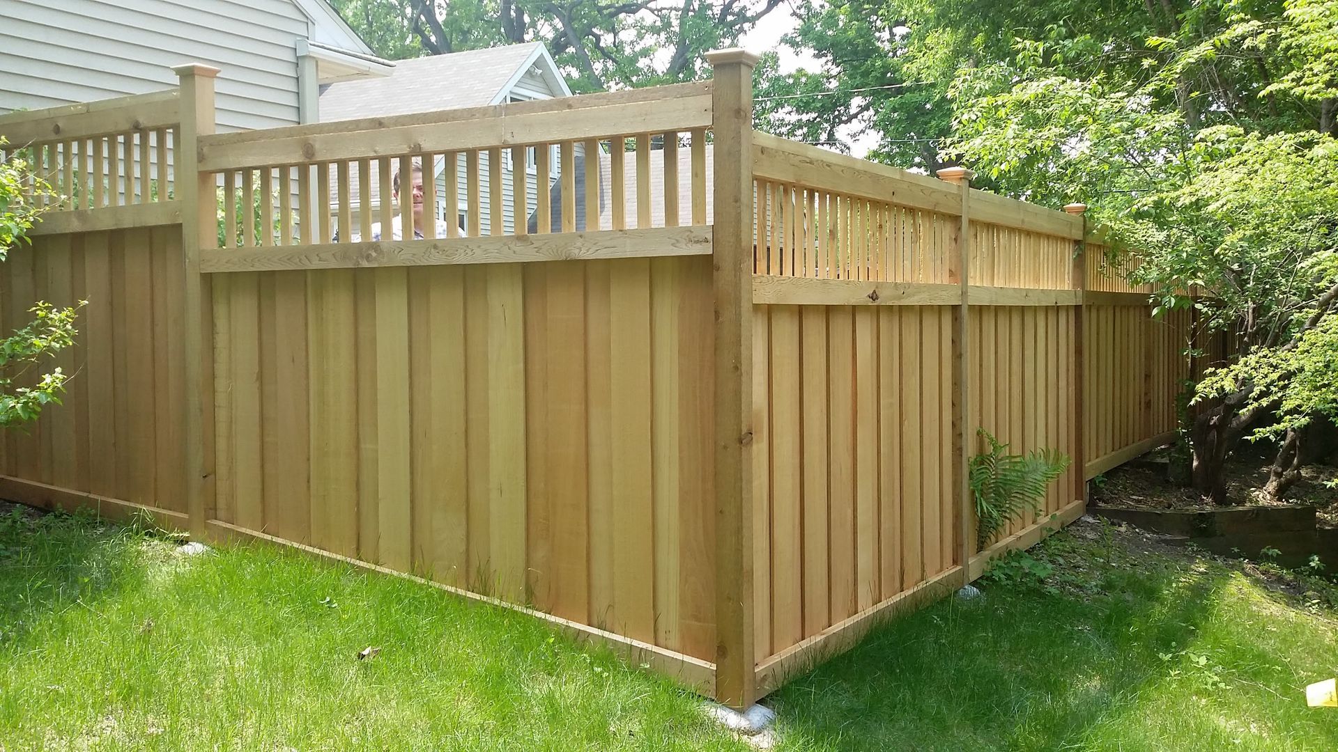Wooden privacy fence with lattice top surrounding a grassy backyard corner
