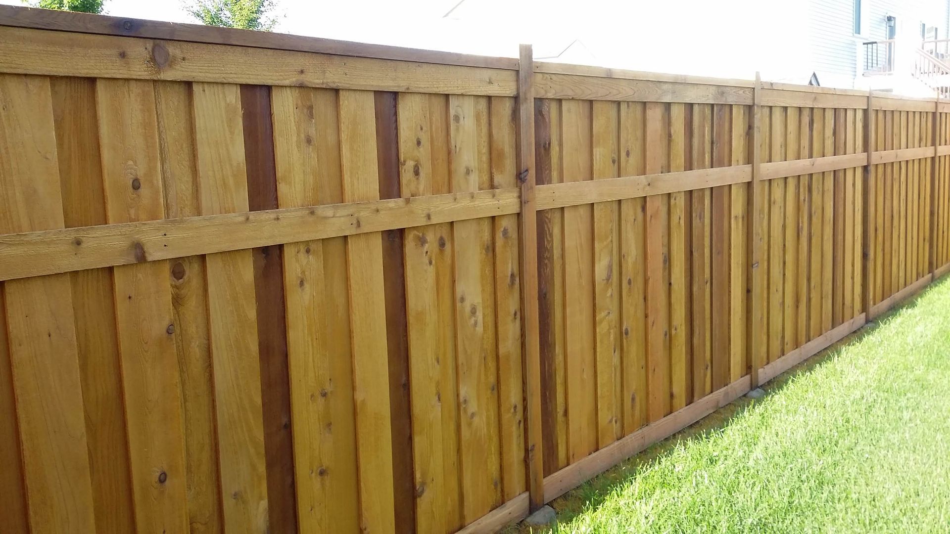 Wooden privacy fence along a grassy yard under a clear sky