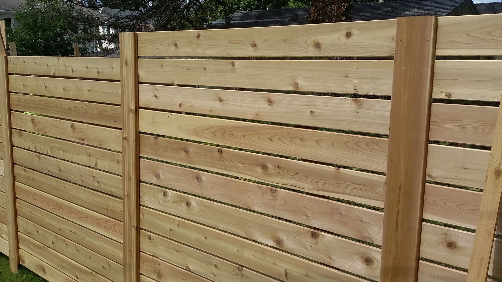 New wooden plank fence with vertical posts in a backyard